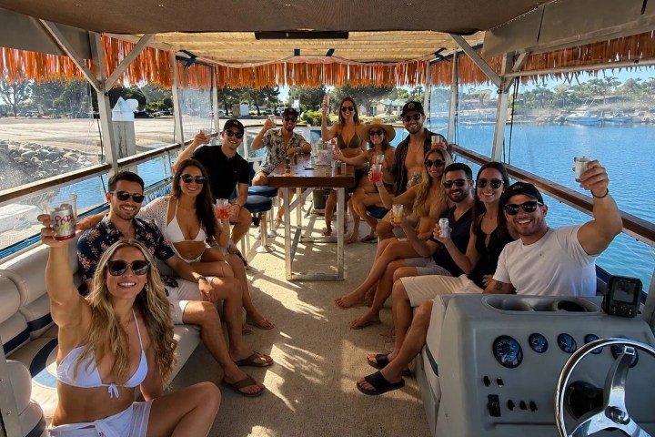 Group of people on a boat, raising glasses, enjoying a sunny day.