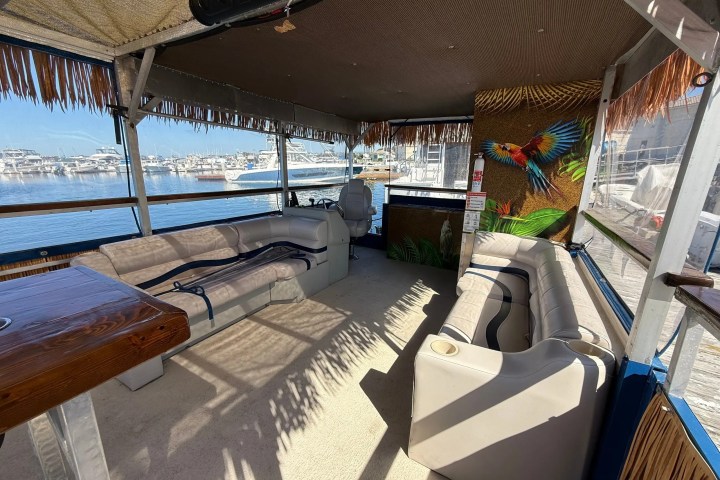 Covered boat deck with seating, tropical mural, and marina view.